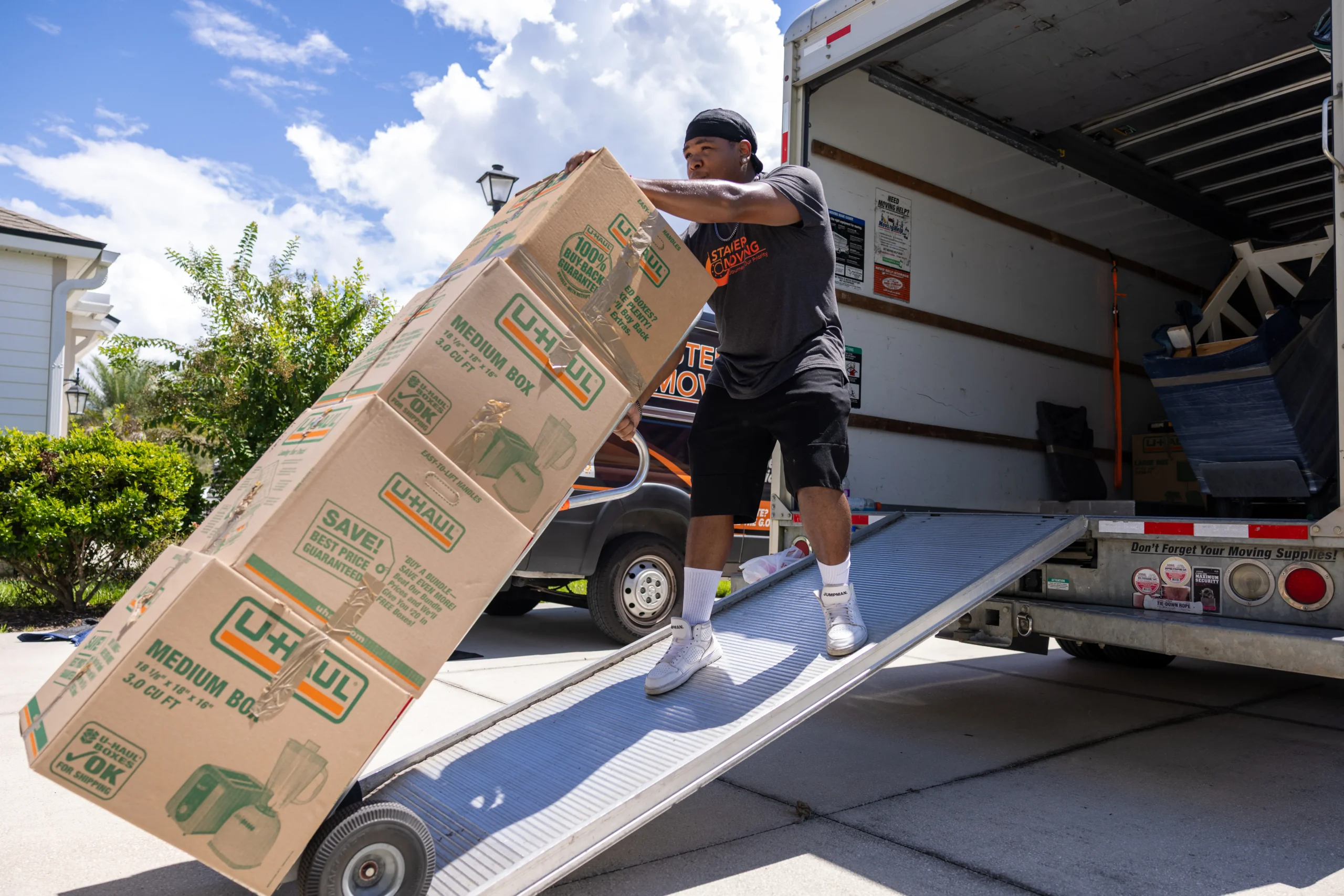 Stair Masters Moving crew member wheeling boxes up a truck ramp during a commercial move
