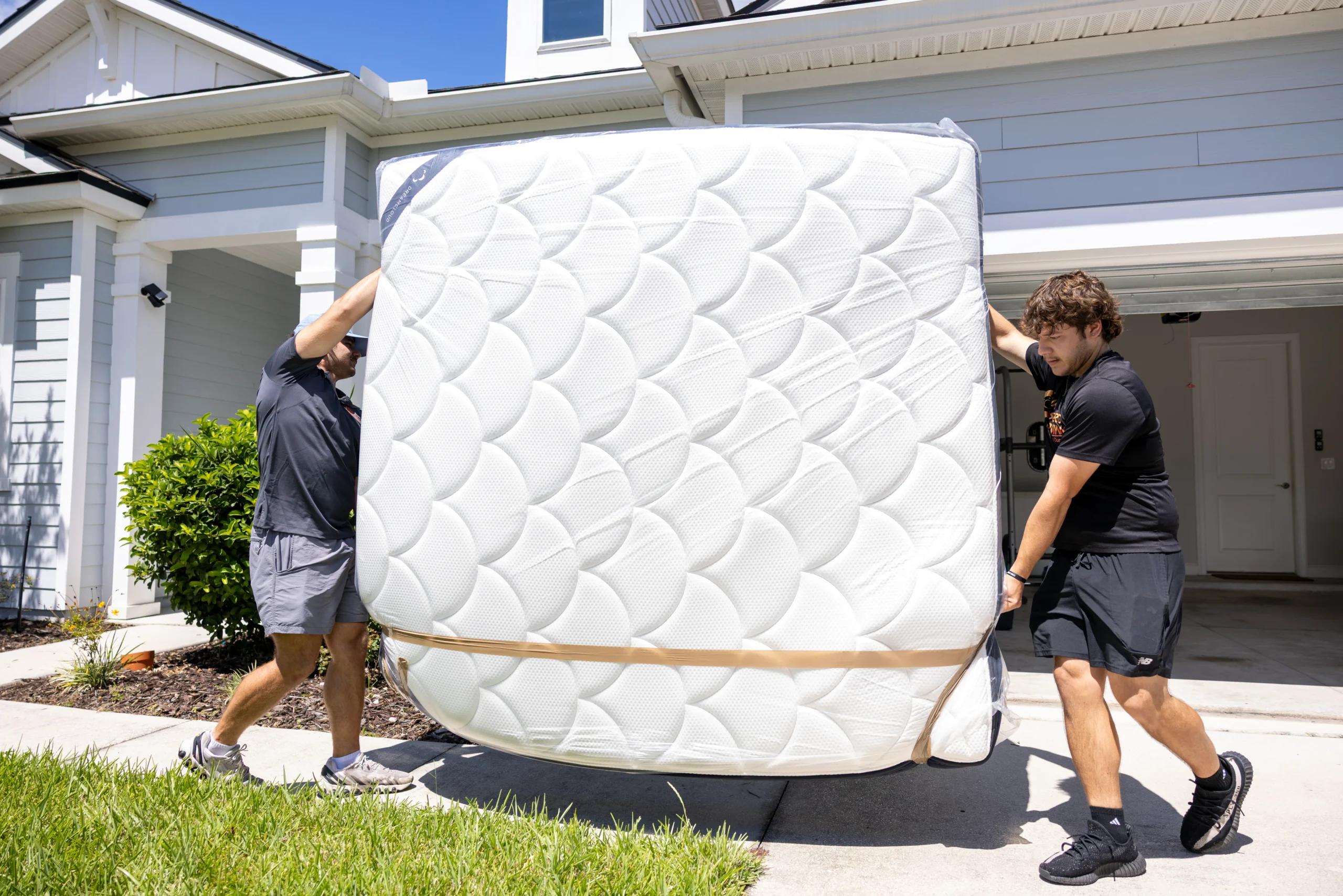 Two Stair Masters Moving crew members carrying a wrapped mattress out of an apartment in Jacksonville, FL