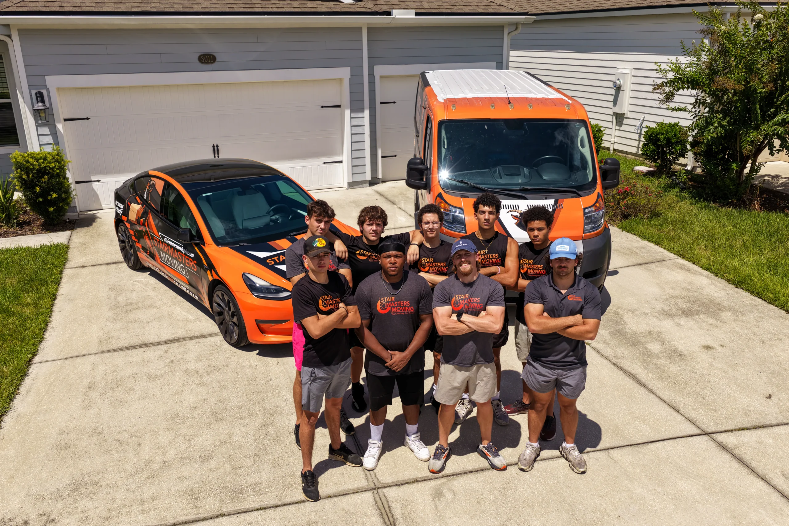 Stair Masters Moving crew standing in front of their branded car and van outside a Jacksonville, FL home