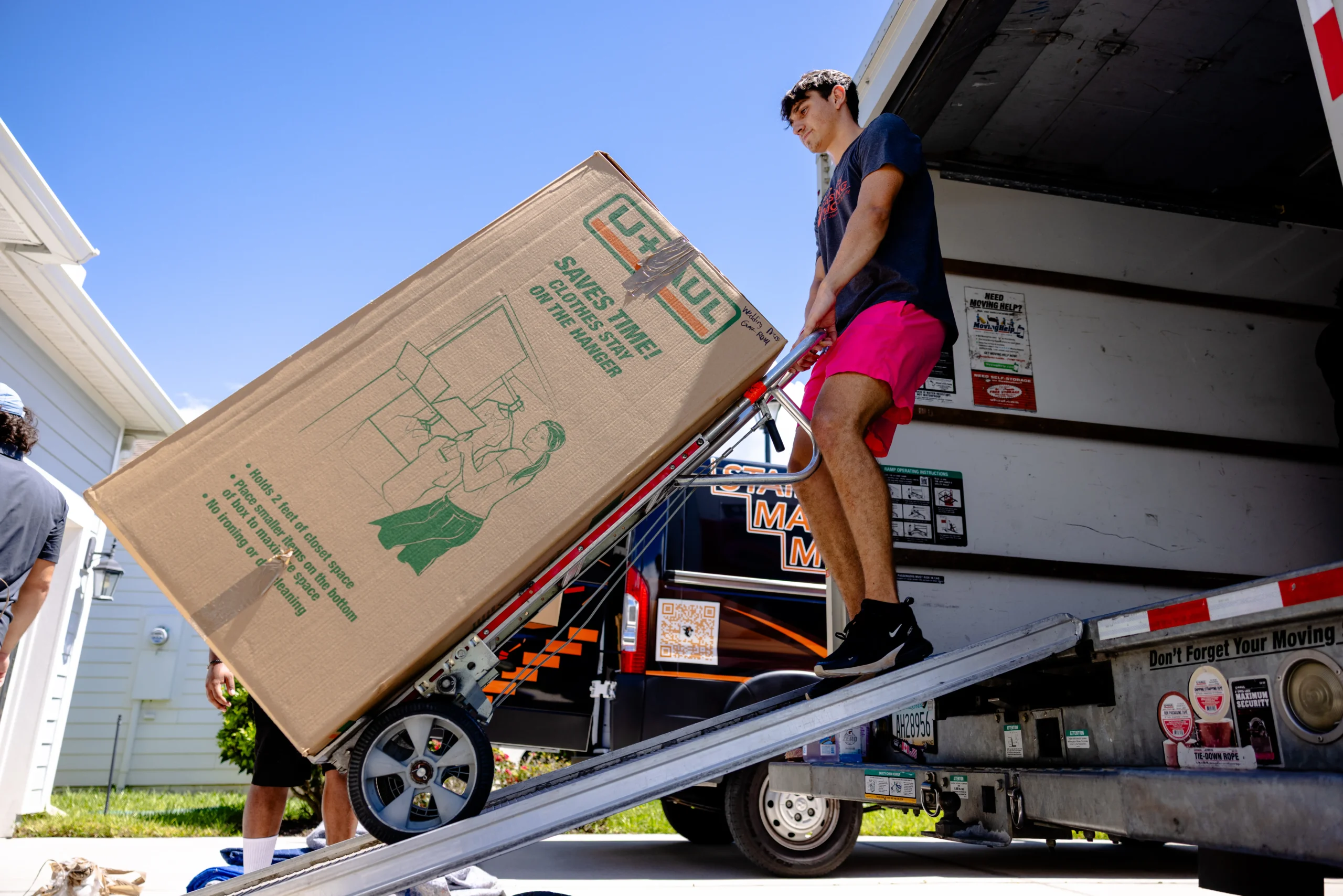 Stair Masters Moving crew member using a hand truck to load a wardrobe box up a ramp